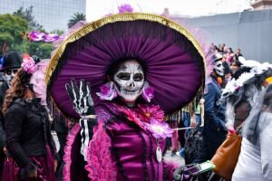 Participante con maquillaje de catrina y sombrero morado en la procesión de 2019.