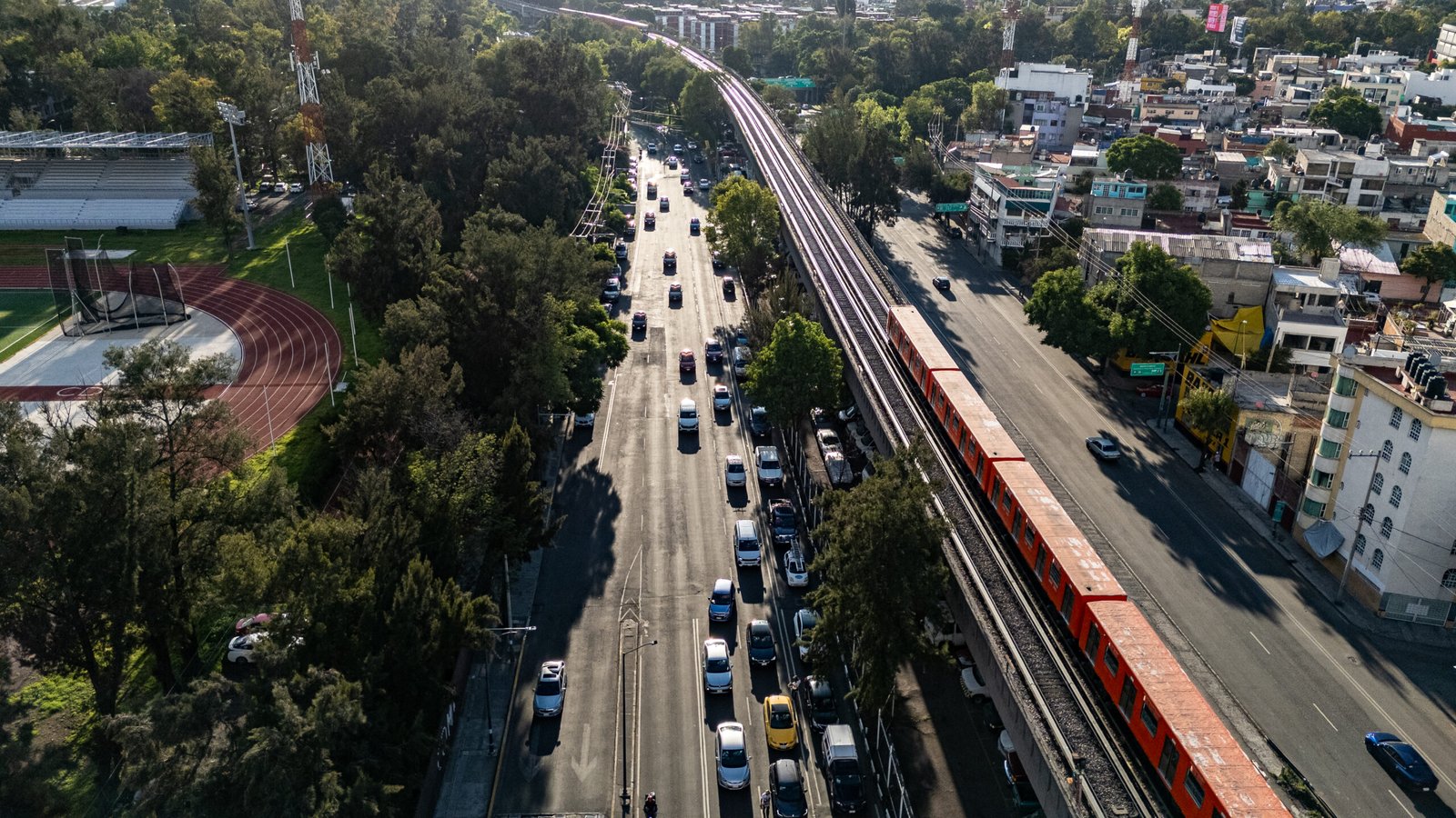 Tren sobre vías elevadas de la Línea 9 junto a Viaducto Río de la Piedad y un recinto deportivo, agosto de 2025.