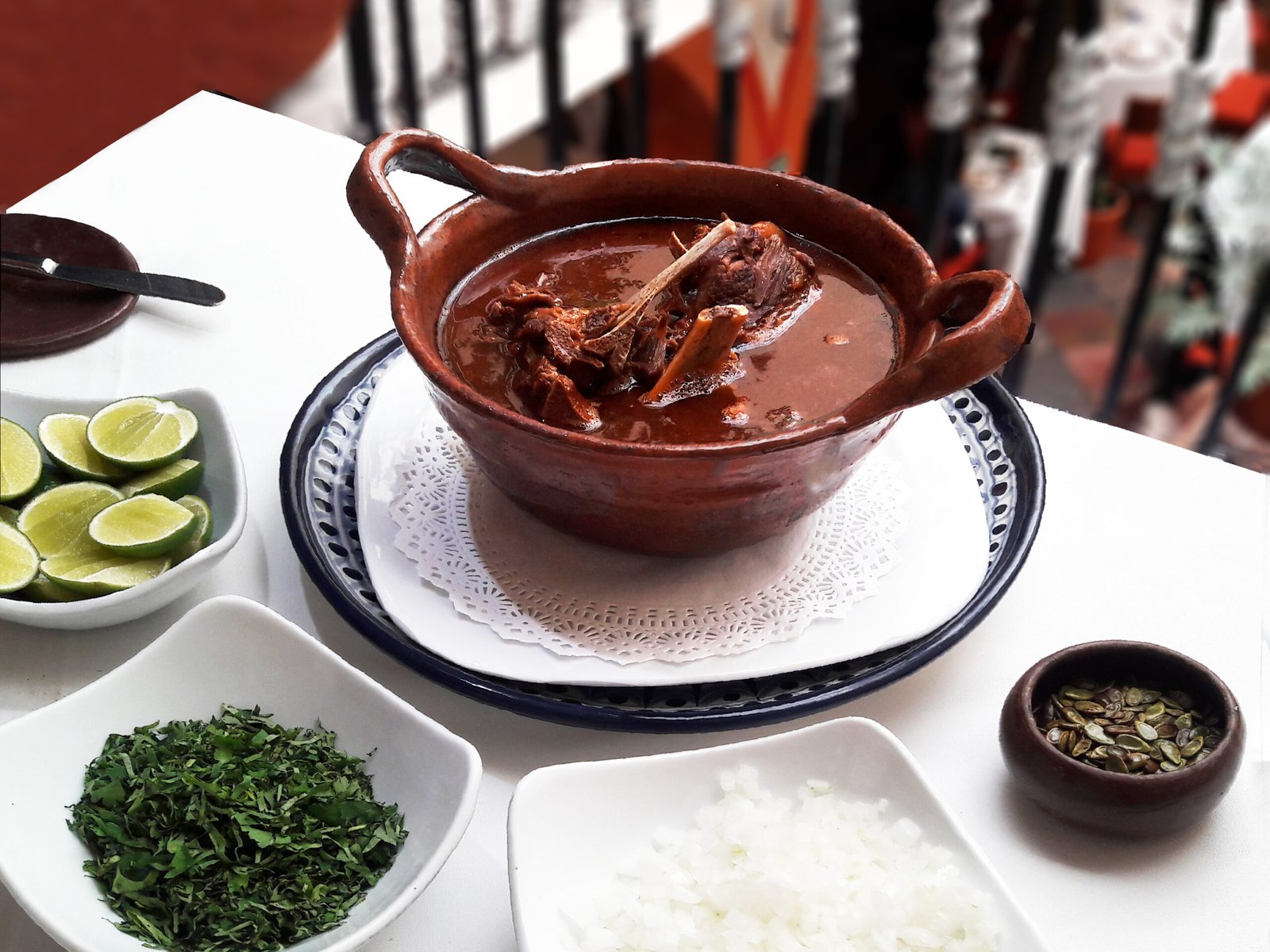 Huaxmole de caderas servido en cazuela, acompañado por limón, cebolla, hierbas y semillas de guaje; fotografía de archivo de 2017.